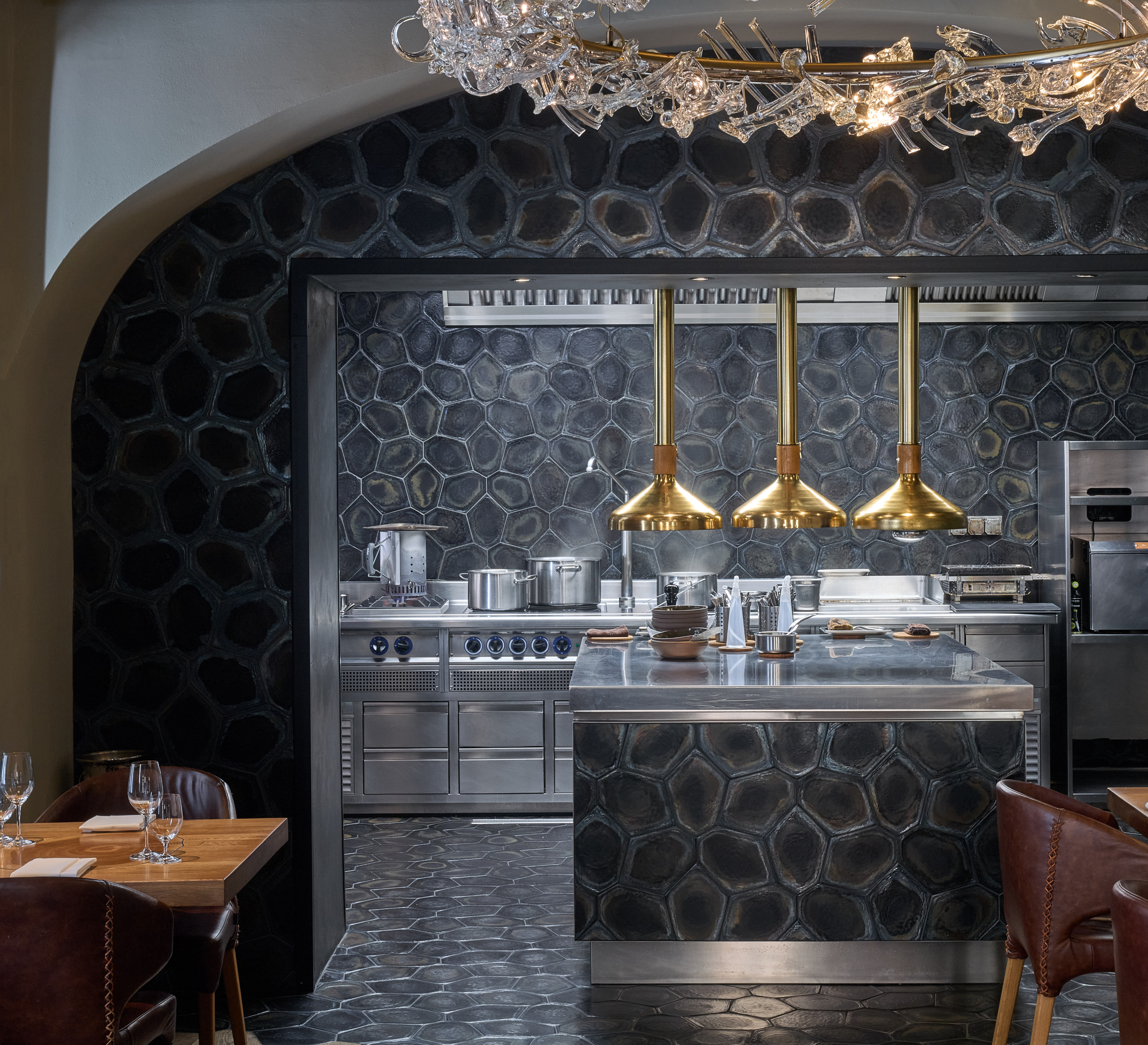 Open kitchen with brass extractor hoods in the restaurant interior.