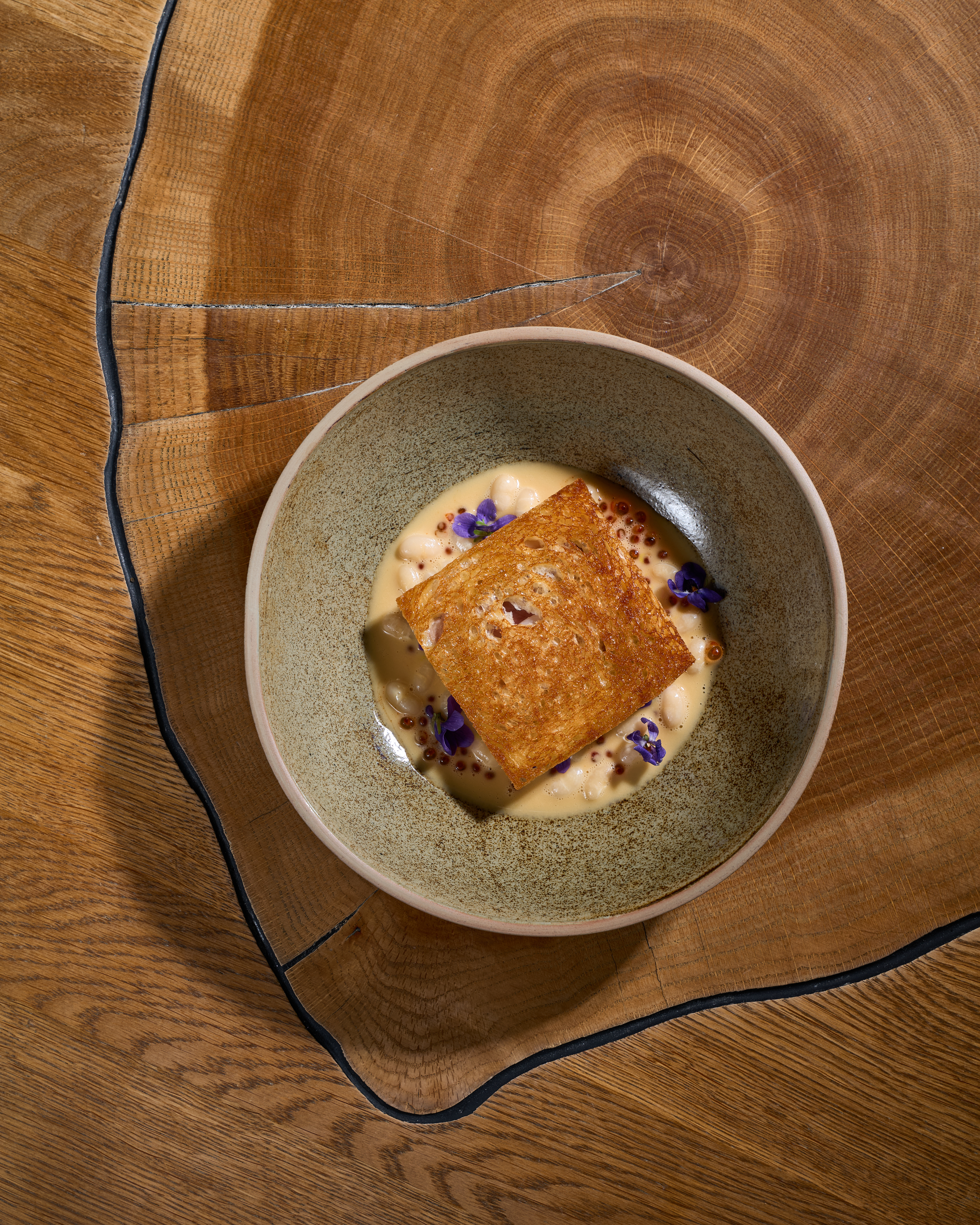 A plated course with a crisp crust, creamy sauce and edible flowers.
