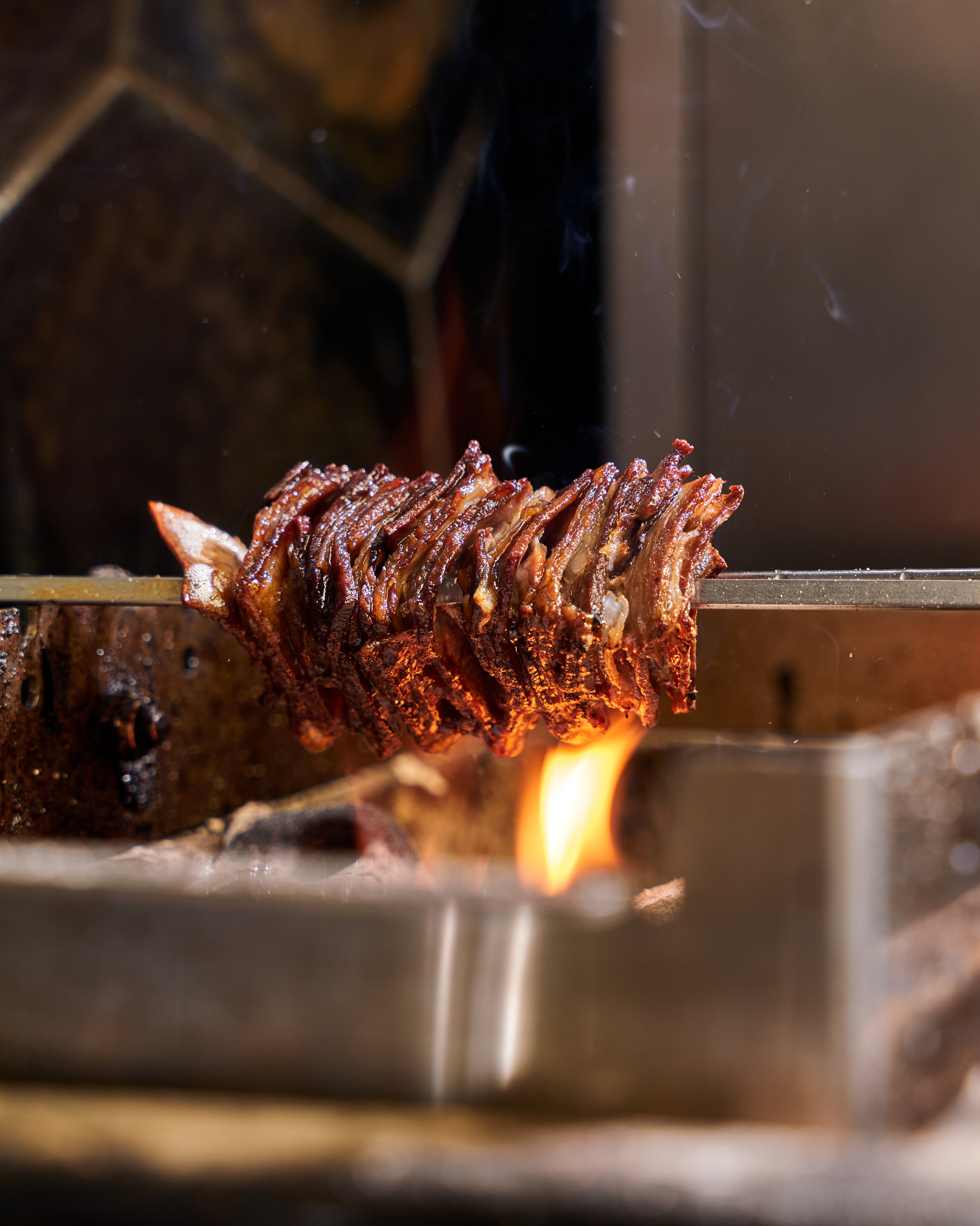 Grilled ribs on a spit over an open flame.