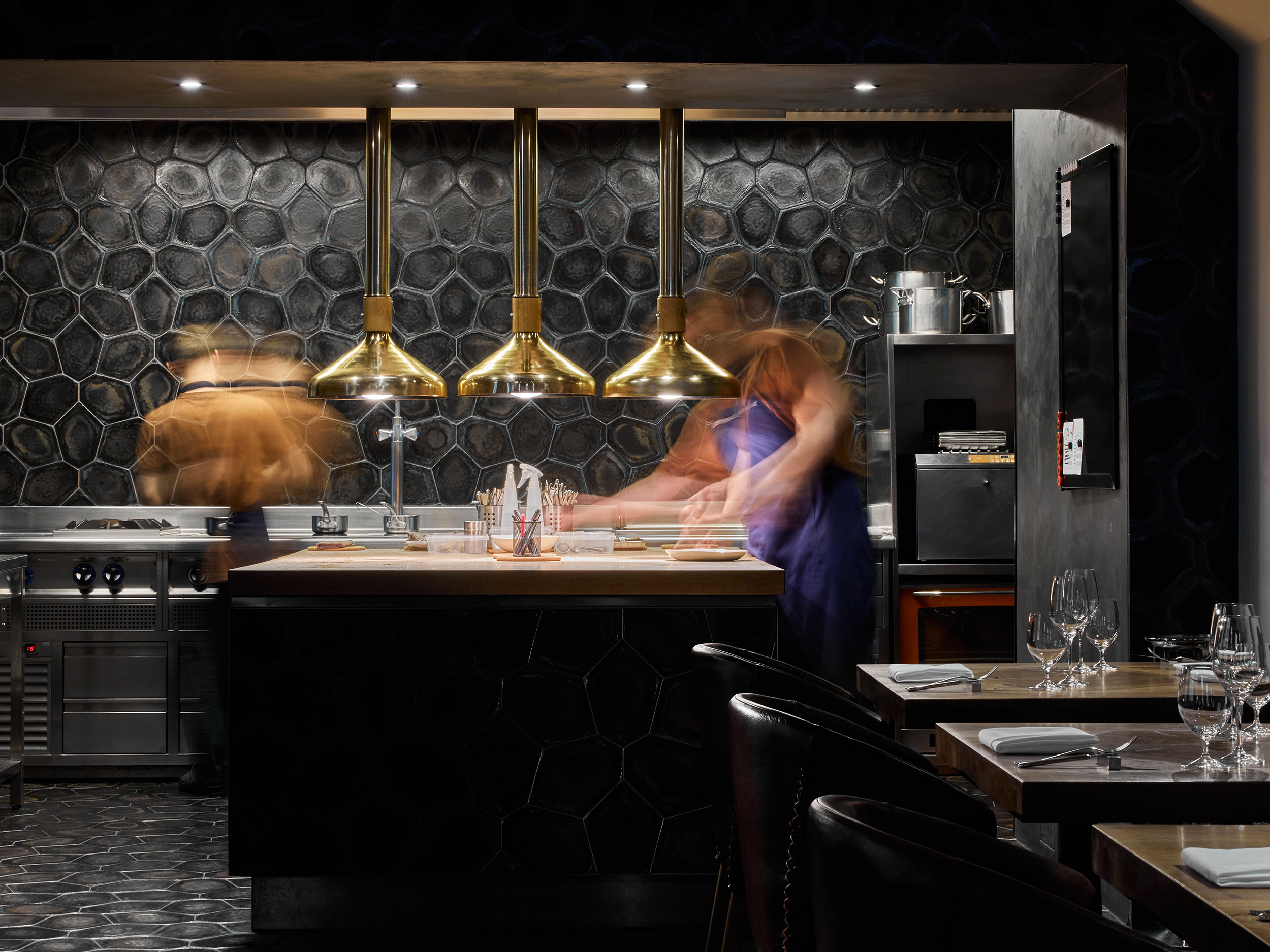 Open restaurant kitchen with chefs captured in motion.
