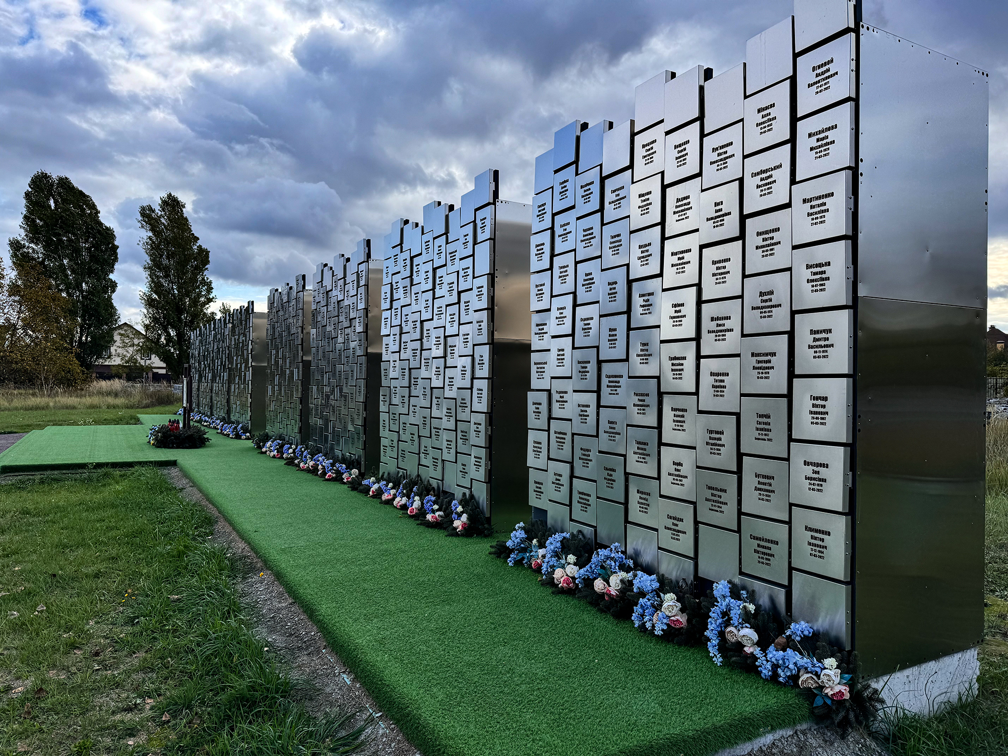 Oficiální památník masakru v Buči. Kde je zelený "koberec" byla před lety vyhloubená jáma, do které Rusové házeli Ukrajince, které zabili. Někteří měli svázané ruce. 