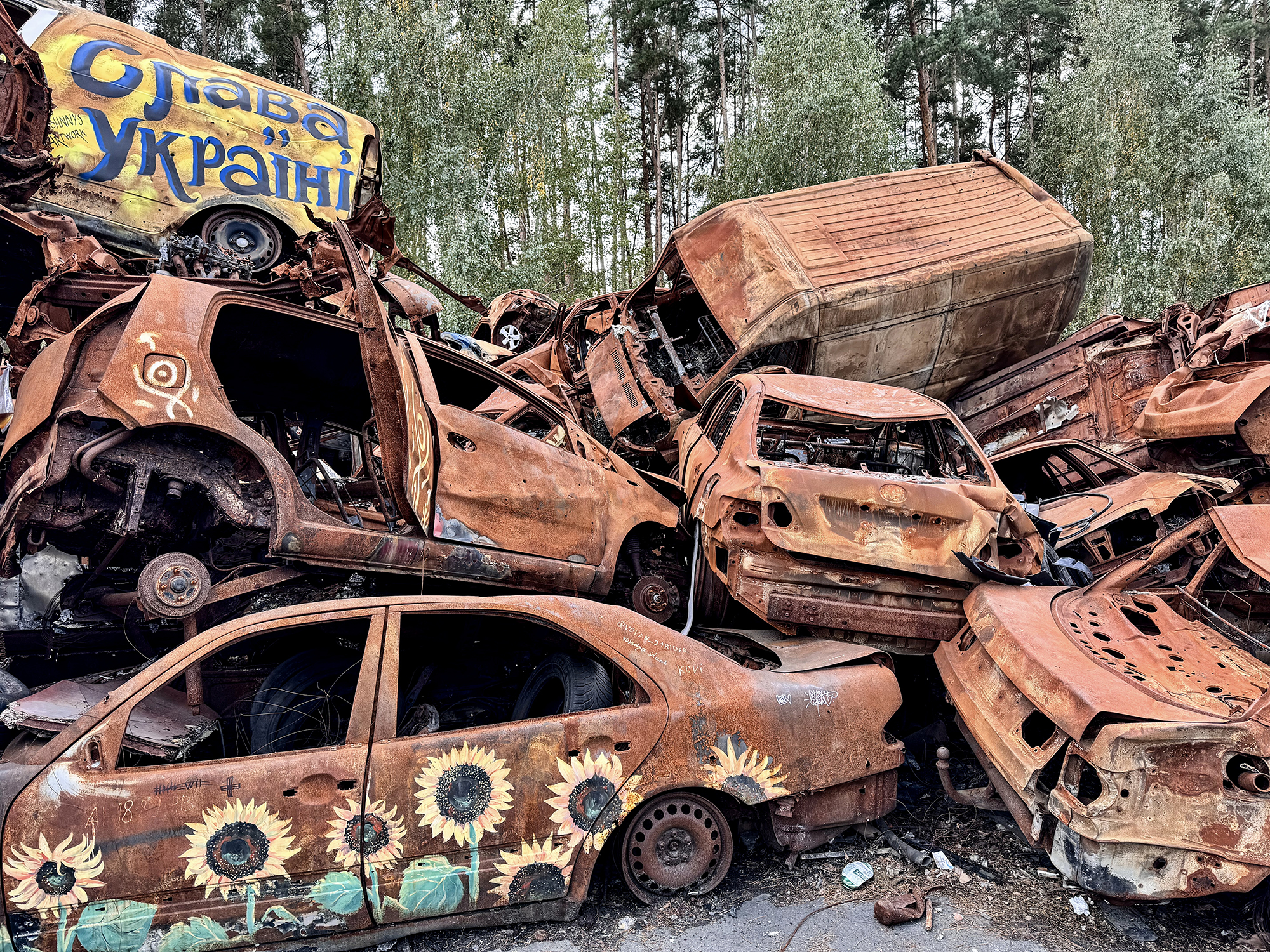 U silnice v Buči, kudy přijížděli Rusové, vznikl spontánní památník obětem. Na jednu hromadu jsou naházená auta, ve kterých se lidé snažili uniknout, ale ruští vojáci je nenechali.